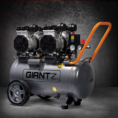 The large, black Giantz 50L Air Compressor 3.0HP Oil-Free Quiet Electric Portable Air Inflator boasts an efficient oilless lubrication system and a spacious 50L compressor. It features two black motors on top, pressure gauges, and a control panel on one side. With two large wheels, a small front support, and an orange handle, it ensures easy maneuverability.