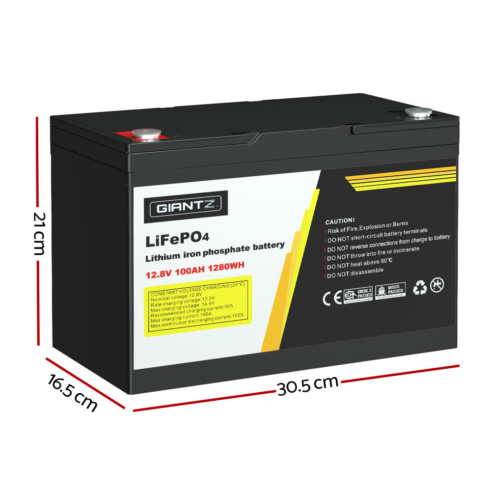 A black Giantz 12V 100Ah Lithium Battery LiFePO4 Deep Cycle Box Solar Caravan Camping with a capacity of 12.8V, 100Ah, and 1280Wh. It has a label with the brand "Giantz," safety warnings, certifications, and handling instructions. Ideal for emergency power or outdoor use, it features two protruding handles on top for easy carrying.