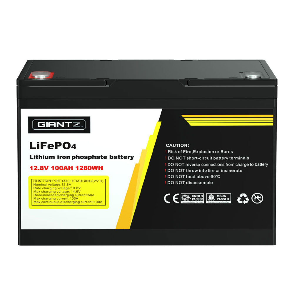 A black Giantz 12V 100Ah Lithium Battery LiFePO4 Deep Cycle Box Solar Caravan Camping with a capacity of 12.8V, 100Ah, and 1280Wh. It has a label with the brand "Giantz," safety warnings, certifications, and handling instructions. Ideal for emergency power or outdoor use, it features two protruding handles on top for easy carrying.