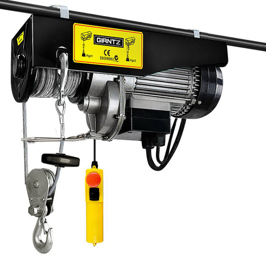 The Giantz Electric Hoist Winch 400/800KG Cable 18M Rope Tool Remote Chain Lifting, perfect for heavy lifting, is mounted on a metal frame. It features a sturdy metallic build with a coiled cable and lifting hook. A yellow wired remote control with a red button ensures easy operation of this 1300W winch.