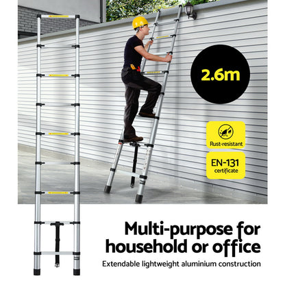 A collapsible Giantz 2.6M Telescopic Ladder Aluminium Extension Extendable Steps Adjustable Height is seen in both its extended and compact forms. The extended ladder, made from premium aluminum alloy, shows multiple rungs with safety labels. The compact version is neatly folded with securing straps and anti-slip end caps for stability.