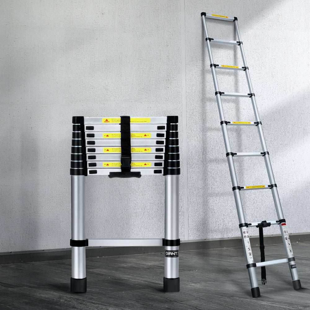 A collapsible Giantz 2.6M Telescopic Ladder Aluminium Extension Extendable Steps Adjustable Height is seen in both its extended and compact forms. The extended ladder, made from premium aluminum alloy, shows multiple rungs with safety labels. The compact version is neatly folded with securing straps and anti-slip end caps for stability.