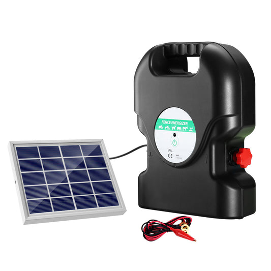 A black, portable Giantz Fence Energiser 20KM Solar Powered 1.2J Electric with a handle on top ensures livestock protection. It's connected to a small solar panel by a cable, employing two red alligator clips attached to black and red wires in front of the waterproof energizer.