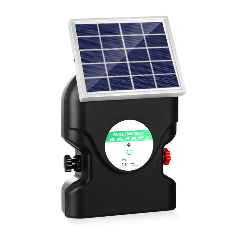 A black, portable Giantz Fence Energiser 20KM Solar Powered 1.2J Electric with a handle on top ensures livestock protection. It's connected to a small solar panel by a cable, employing two red alligator clips attached to black and red wires in front of the waterproof energizer.