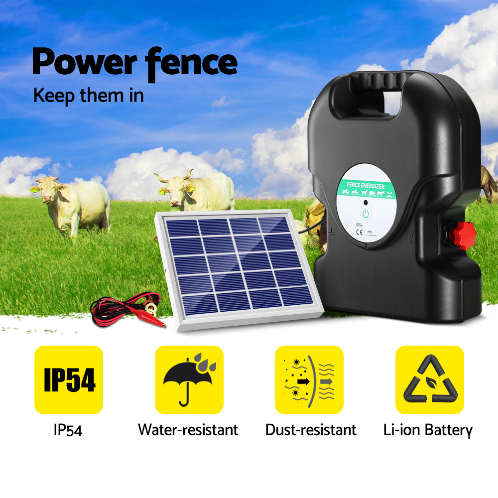 A black, portable Giantz Fence Energiser 20KM Solar Powered 1.2J Electric with a handle on top ensures livestock protection. It's connected to a small solar panel by a cable, employing two red alligator clips attached to black and red wires in front of the waterproof energizer.