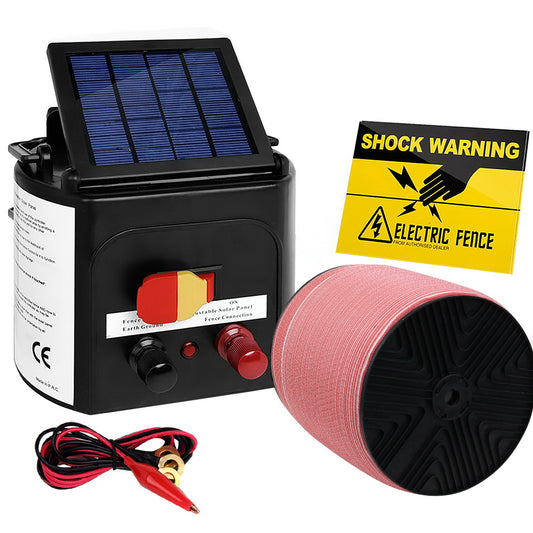 A Giantz Fence Energiser 3KM Solar Powered Electric 1200M Poly Tape featuring a monocrystalline solar panel, a red and black spool of wire, red and black alligator clip cables, and a yellow "Shock Warning" sign with a lightning bolt symbol. Ideal for livestock containment, it includes control knobs on the front for easy adjustment.