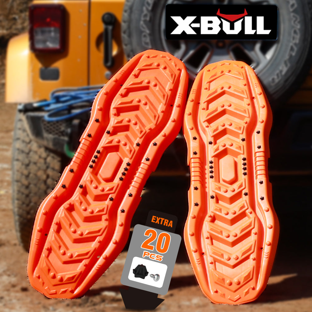 The image showcases two orange X-BULL Recovery Boards tracks kit 4WD Sand Snow trucks Mud Car Vehicles with UV resistance, designed for off-road 4X4 vehicles. Positioned upright against a yellow jeep in a rugged outdoor setting, the text highlights the product name "X-BULL" and mentions an extra 20 pieces of hardware included.