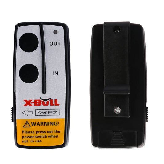 A front and back view of the black and grey X-BULL 2x Wireless Winch Remote Control 12 Volt 150ft Handset Switch 4wd. The front has two black buttons labeled "IN" and "OUT," and a "Power switch." A yellow warning label advises pressing the power switch when not in use. The back has a clip and a screw.