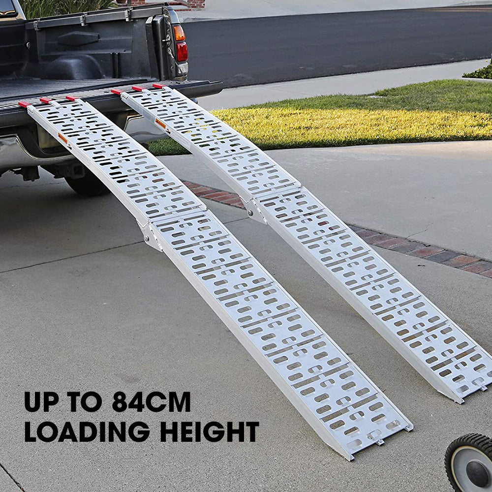 Two aluminium folding ramps are shown: one unfolded and the other partially folded, both with perforated surfaces and small red anti-slip tabs at the ends. These BULLET 2.3m Aluminium Loading Ramps, 680kg Rated, for Trailer ATV Quad Bike Buggy, 2 Pieces are designed to assist in loading items into elevated areas such as trucks or trailers, featuring safety cam lock straps for added security.