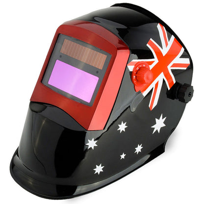 The ROSSI Solar Auto Darkening Welding Helmet MIG/ARC/TIG Welder Machine Mask, featuring a sleek black design with red trim around the viewing area, proudly displays the Australian flag with its iconic red, white, and blue design, including the Union Jack and Southern Cross stars. This helmet also boasts automatic tinting and adjustable knobs on the sides.