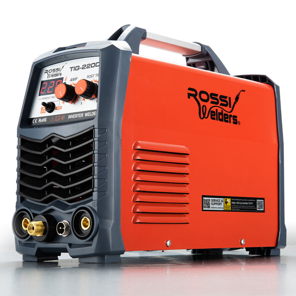 A ROSSI 220A Welder Stick GTAW Gas Tungsten Arc Welding Machine Inverter TIG MMA by Rossi Welders sits on a reflective surface. The machine, labeled as the ROSSI 220A Welder Stick GTAW Gas Tungsten Arc Welding Machine Inverter TIG MMA, is mainly red with gray accents and features a digital display, various control knobs, and connectors on its front panel. This 220Amp iGBT inverter welder ensures precise and efficient performance.