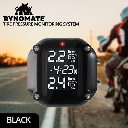 A close-up image of a digital display device from a RYNOMATE Tire Pressure Monitoring System (Motorcycle 2 Sensor) RNM-TPMS-101-LBD shows various measurements. The screen displays pressure readings in bar units: 2.2 for FW and 2.4 for RW, enhancing increased fuel efficiency. It also shows two temperature readings at 65°C and the current time, 4:23 PM. The device has a black frame.