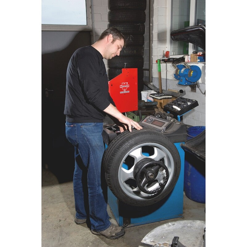 Black plastic spool with a roll of white, perforated material partially unrolled. The spool has a central hub and radial spokes, reminiscent of aluminium rims. The material on the spool appears to be a flexible, segmented strip that resembles Wurth 1000pcs Roll of Wheel Balance Weights Stick-On Adhesive Car (5g).