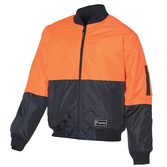 An HUSKI 3M Flyer Fully Waterproof Bomber Jacket Hi Vis Work Quilted Lining - Orange - M (97) with a front zipper, ribbed cuffs, and a collar. The jacket features a black rectangular patch with the text "HUSKI" on the front, has a zippered pocket on the upper left sleeve, and boasts quilted lining for added warmth.