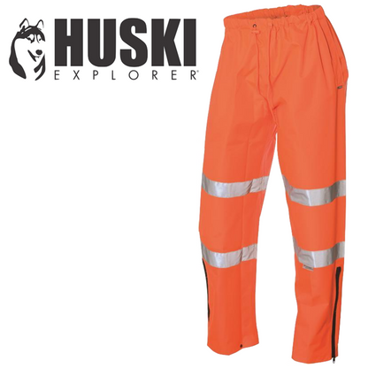 A person wearing bright orange Huski Mens Tarmac Hi Vis Trousers Pants High Visibility Safety Pants - Orange - 5XL (117cm) with reflective stripes around the lower thighs. The person is shown from the back, with visible side pockets and zippers near the ankles of the 5XL pants.